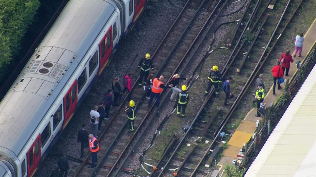 In this aerial image made from video, emergency workers help people to disembark a train near the Parsons Green Underground Station after an explosion in London Friday, Sept. 15, 2017. A reported explosion at a train station sent commuters stampeding in panic, injuring several people at the height of London's morning rush hour, and police said they were investigating it as a terrorist attack. (Pool via AP)