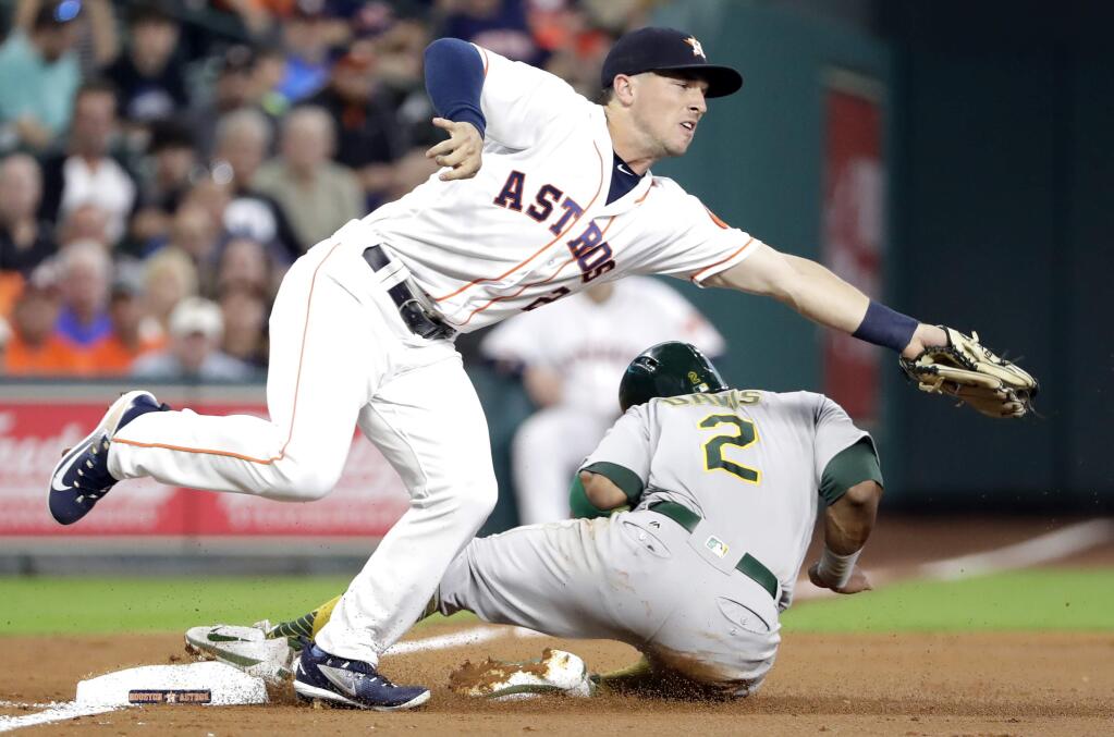 Oakland Athletics' Khris Davis, right, slides safely into third base on a wild pitch thrown by Houston Astros starting pitcher Mike Fiers as third baseman Alex Bregman (2) reaches for the throw from catcher Brian McCann during the second inning of a baseball game Tuesday, June 27, 2017, in Houston. (AP Photo/David J. Phillip)