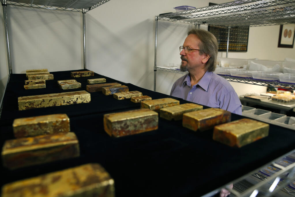 FILE - Chief scientist Bob Evans looks at gold bars recovered from theS.S. Central Americasteamship that went down in a hurricane in 1857 in a laboratory on Jan. 23, 2018, in Santa Ana, Calif. Riches entombed in the wreckage of the pre-Civil War steamship for more than a century will begin to hit the auction block for the first time Dec. 3, 2022, when more than 300 Gold Rush-era artifacts are offered for public sale in Reno, Nev. (AP Photo/Jae C. Hong, File)