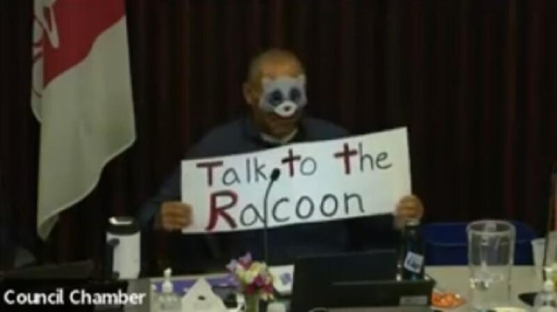 Santa Rosa City Schools Trustee Ed Sheffield donned a raccoon mask and held up a sign that said “Talk to the Racoon” during a Wednesday board meeting. (Santa Rosa City Schools via YouTube screenshot)