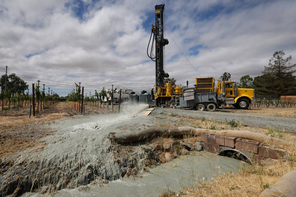 A crew from Weeks Drilling & Pump Co. test a new well, pumping into a self-contained ditch at a vineyard property near Sonoma on Tuesday, June 22, 2021.  (Christopher Chung / The Press Democrat)