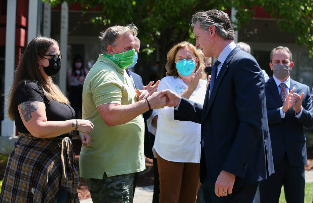California Governor Gavin Newsom, right, fist bumps with  Elderberry Commons residents Douglas Stenberg and Claire Fulkerth after his press conference in Sebastopol on Monday, July 19, 2021.  (Christopher Chung/ The Press Democrat)