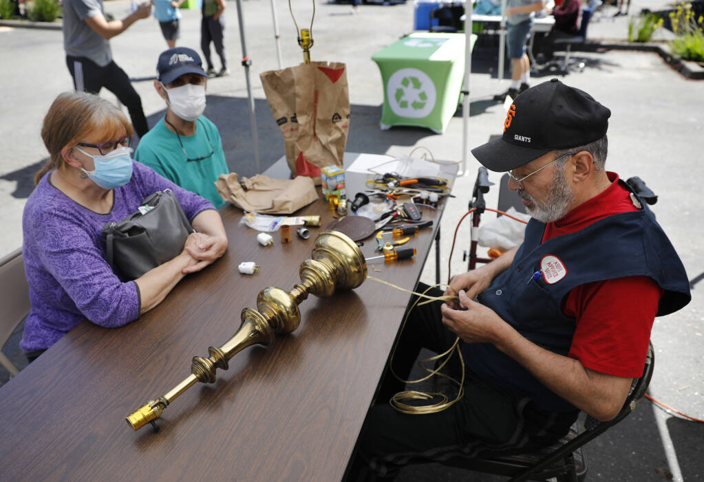 Farid Asef of Asef's Appliance Service repairs a brass lamp from the 1980s for Vivianne Nelson and Michael Teller during a Fix-it Clinic, hosted by Zero Waste Sonoma in Santa Rosa, Calif., on Saturday, May 14, 2022. (Beth Schlanker/The Press Democrat)