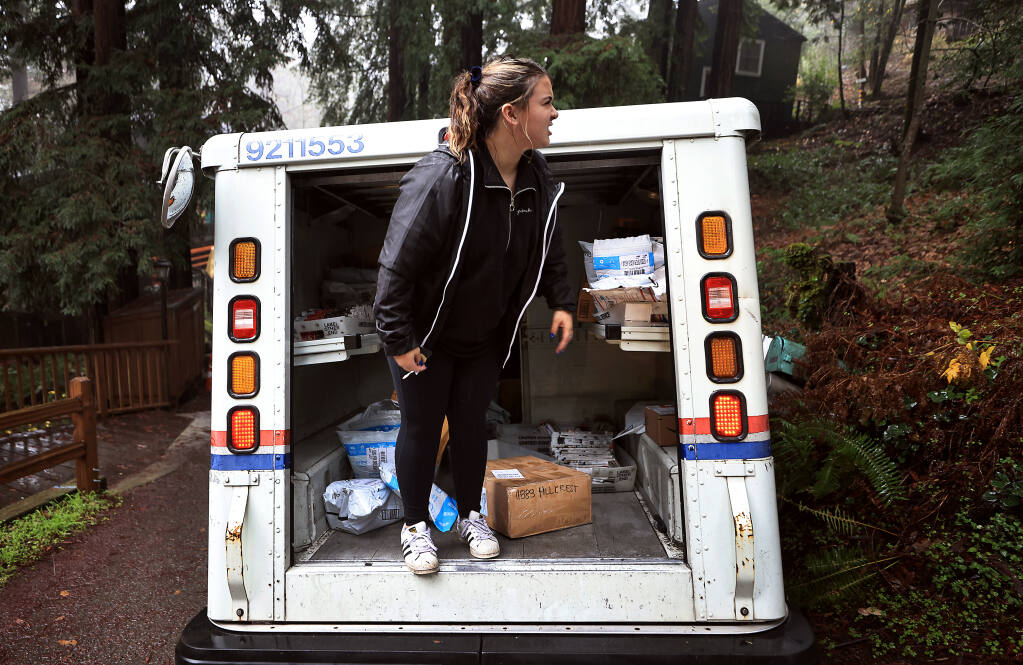 United State Postal Service mail carrier Sierra Gage eyes her next package and mail delivery in the twisty mountainous narrow roads of Summerhome Park near Forestville, Wednesday, Dec. 15, 2021. "It's my favorite route," Gage quips. (KENT PORTER/THE PRESS DEMOCRAT)
