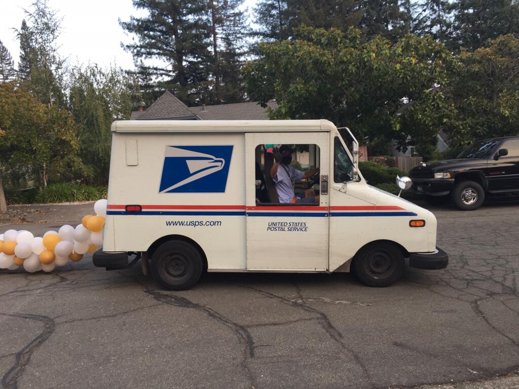 On his last day on the job, USPS carrier Tim Vega waves from the delivery van to which patrons tied a tail of balloons. (Beth Pitchford)