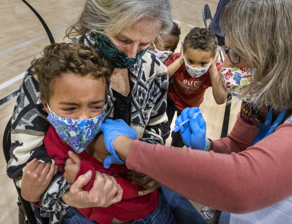 Martha Curtis holds onto her brave son Jeremiah, 5, as he receives his COVID-19 vaccine from R.N. Marit Dirado while his siblings Dasha, 3, and Josiah 4, look on in horror at a clinic at the Guerneville Elementary school on Tuesday, November 9, 2021.    (Photo by John Burgess/The Press Democrat)