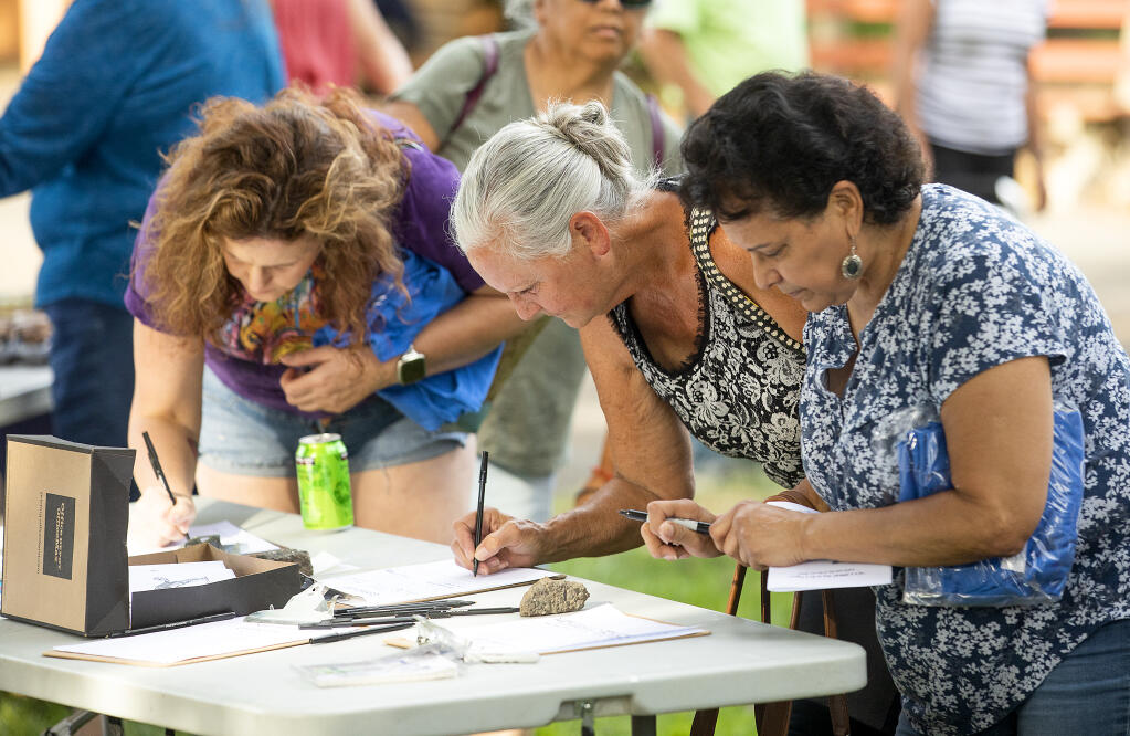From left, Amy Mashall, class of '92, Sheila Wright, '69, and Mario Castro, '70, add their names to petitions and group lists opposing, the changing of the name of their alma mater, Analy High School, at Ives Park in Sebastopol on Wednesday, June 16, 2021.  (Photo by John Burgess/The Press Democrat)