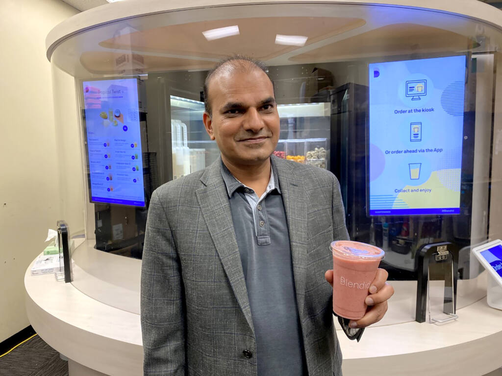Vipin Jain, CEO and cofounder of Blendid, holds a smoothie on Tuesday, June 30, 2020, in Sunnyvale, Calif.,  made by his company’s robotic kiosk that makes blended fruit drinks with no human intervention. “I expect in the next two years you will see pretty significant robotic adoption in the food space because of COVID,” said Jain.  (AP Photo/Terry Chea)