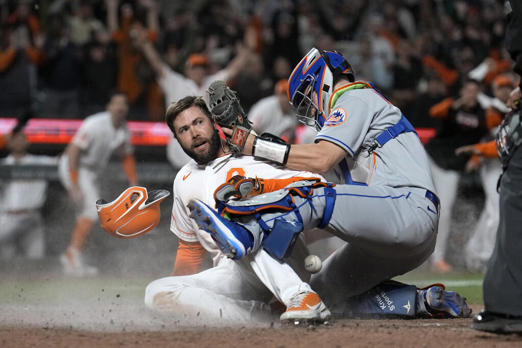 The Giants’ Darin Ruf scores the winning run as New York Mets catcher Tomas Nido, right, drops the ball during the ninth inning in San Francisco on Tuesday, May 24, 2022. The Giants won 13-12. (AP Photo/Tony Avelar)