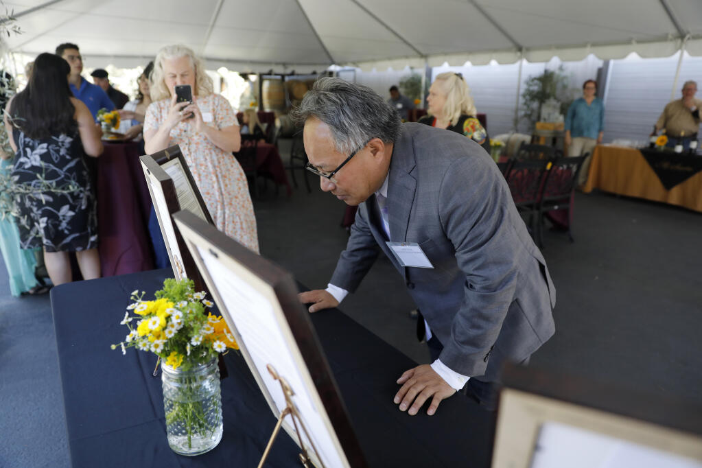 Former Sonoma Mayor Jack Ding, now a member of City Council, takes a closer look at a framed congressional record of remarks by U.S. Rep. Mike Thompson, which honors Ding as part of the "American Dream Awards" event at Mi Sueño Winery in Napa, Sunday, July 9, 2023. (Beth Schlanker / The Press Democrat)