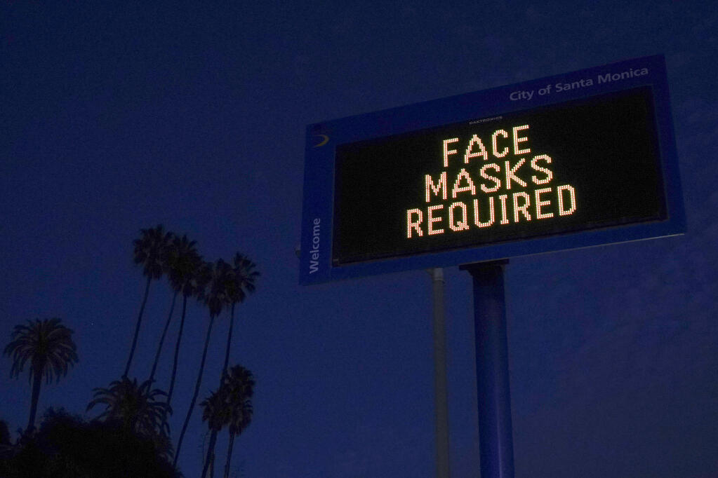 A sign reminding people to wear a mask stands along the Pacific Coast Highway in Santa Monica, Calif., Tuesday, Dec. 8, 2020. Most of California entered a new lockdown this week in an effort to curb spiraling coronavirus infections and hospitalizations. (AP Photo/Jae C. Hong)
