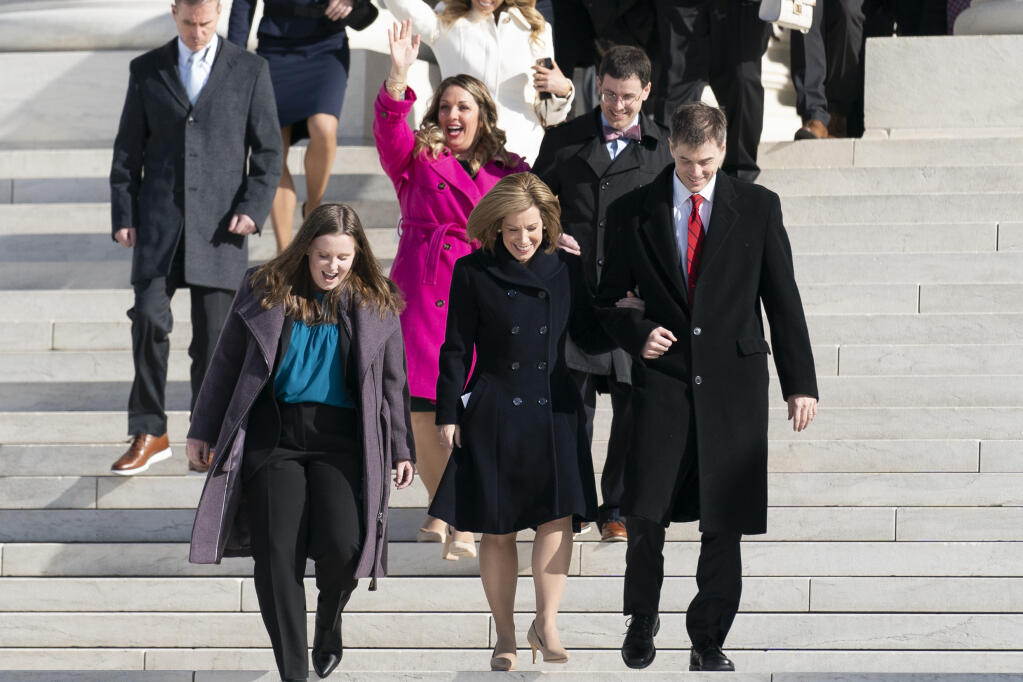 Lorie Smith, a Christian graphic artist and website designer in Colorado, center in pink, walks out of the Supreme Court in Washington, Monday, Dec. 5, 2022, after her case was heard before the Supreme Court. The Supreme Court is hearing the case of Smith who objects to designing wedding websites for gay couples, that's the latest clash of religion and gay rights to land at the highest court. (AP Photo/Andrew Harnik)