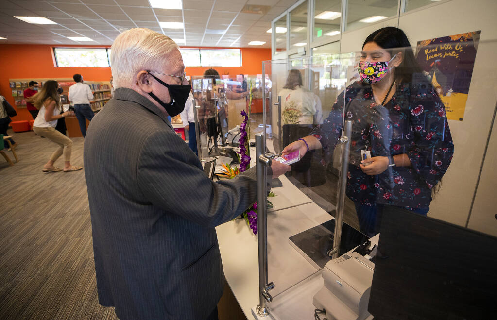 Dave Cahill checks out the second book from librarian Guadlaupe Guzman at the new Roseland Regional Library  on Monday, September 13, 2021. (Photo by John Burgess/The Press Democrat)