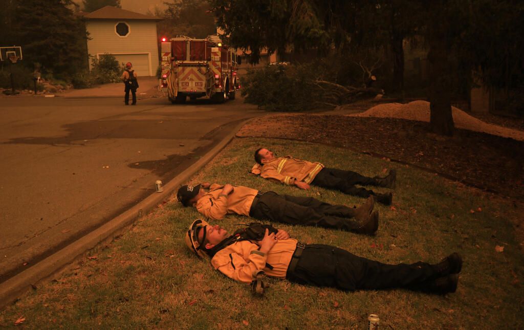 Healdsburg firefighters Mike Jacobs, Dean De La Montoya and Bennett Lida rest after saving structures overnight on Beaumont Way, Monday, Sept. 27, 2020 in Santa Rosa. Only one home was lost on the block as the Glass fire roared in to Rincon Valley overnight. (Kent Porter / The Press Democrat) 2020
