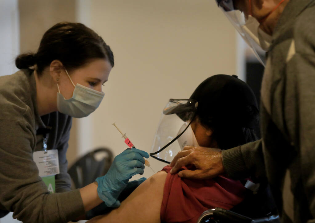 Registered nurse Morgan Longacre injects the Modena vaccine in to Meera Goyan of Santa Rosa during a Sutter Santa Rosa Regional Hospital COVID-19 vaccination clinic at the Luther Burbank Center in Santa Rosa, Tuesday, Feb. 9, 2021.Her husband Gaeshav, right, also received the vaccine.   (Kent Porter / The Press Democrat) 2021