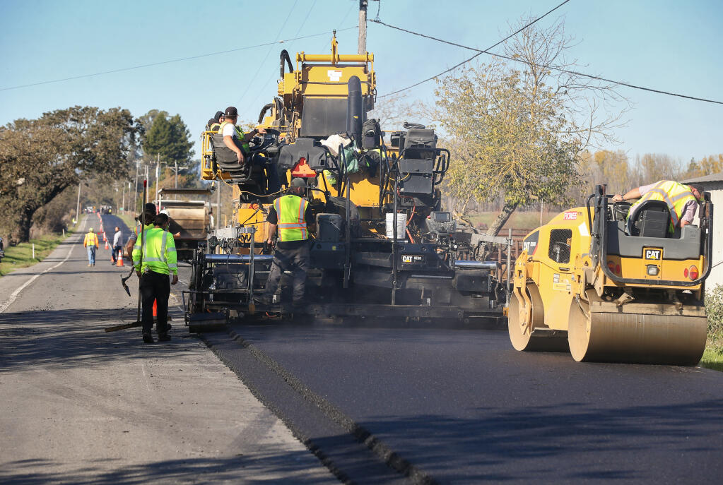 An Argonaut Constructors asphalt paving crew overlay asphalt on Llano Road, north of Todd Road, in Santa Rosa, Monday, Nov. 27, 2023.  (Christopher Chung / The Press Democrat file)