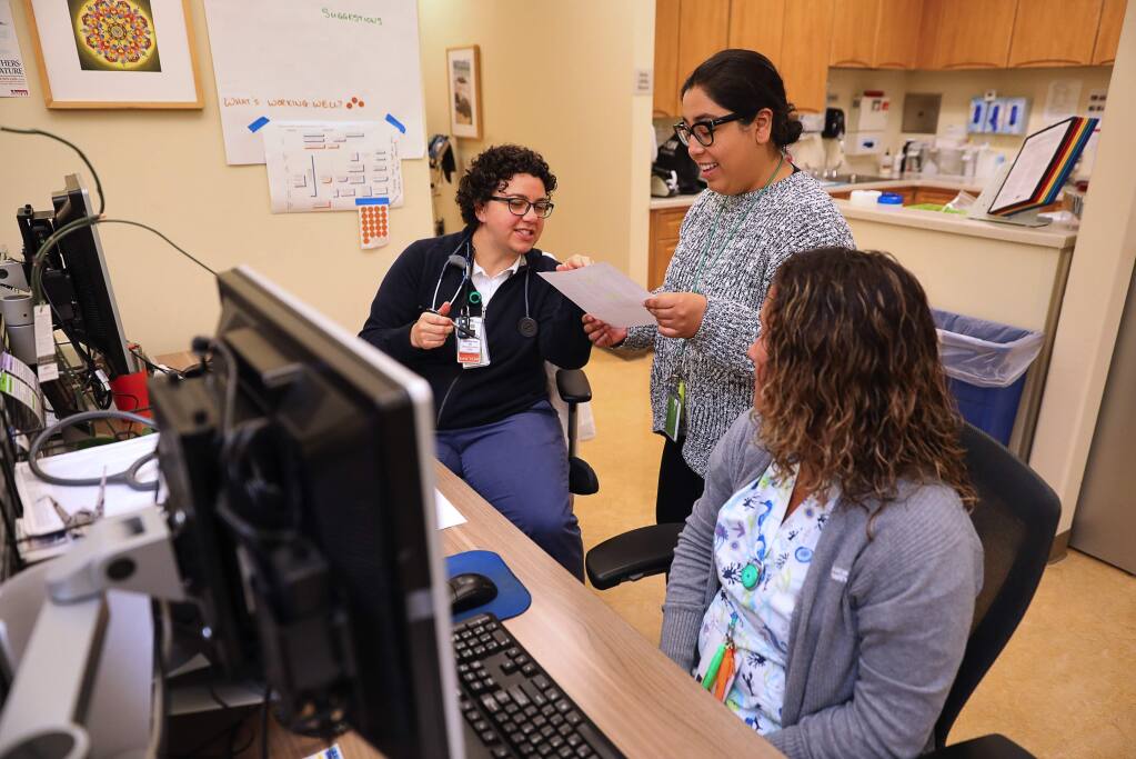 Clinical informatics officer Dr. Danielle Oryn, left, huddles with patient navigator Stephanie Gallegos and medical assistant Brenda Gonzalez to discuss their daily strategy at the start of their day at the Petaluma Health Center, in Petaluma on Tuesday, August 22, 2017. (Christopher Chung/ The Press Democrat)