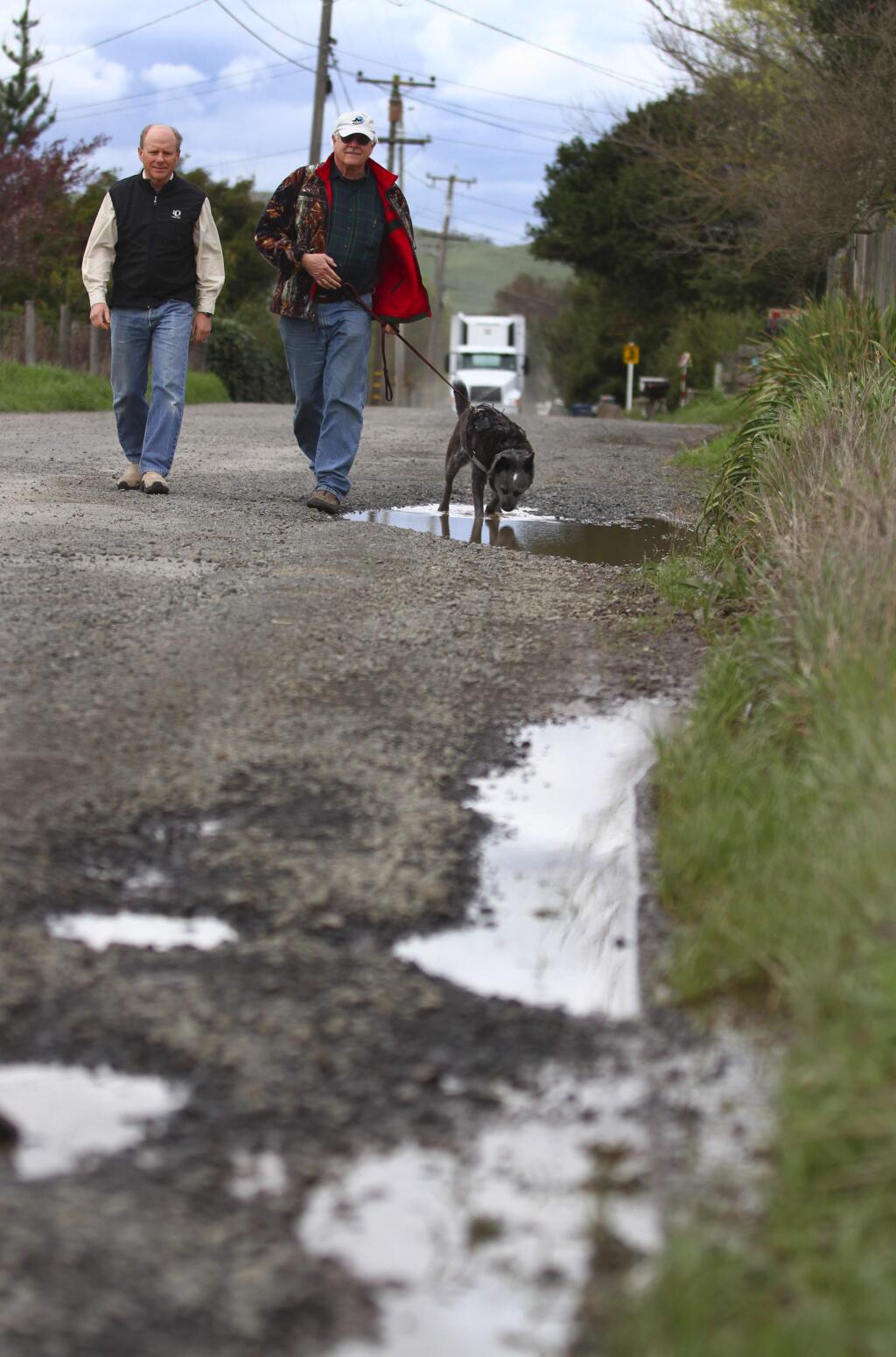 Michael Troy and Craig Harrison walk Cavanaugh Lane in Petaluma with Harrison's dog Tater. The have formed Save Our Sonoma Roads to exert pressure on local government to upkeep the roads.