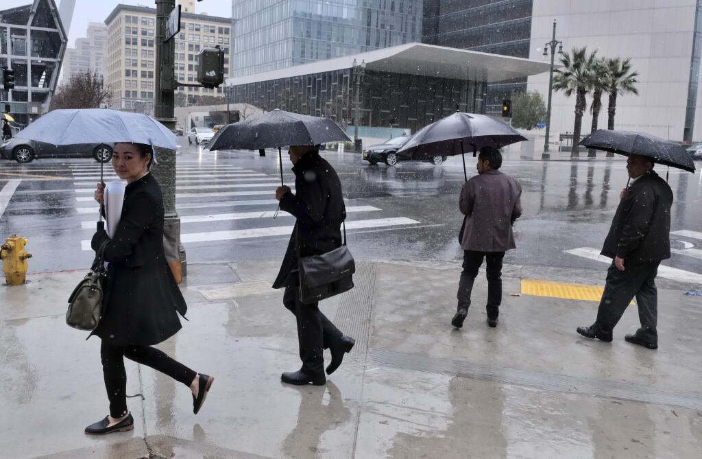 Pedestrians make their way across a street in the pouring rain in downtown Los Angeles on Wednesday, March 21, 2018. The storm came ashore on the central coast and spread south into the Los Angeles region and north through San Francisco Bay, fed by a long plume of subtropical moisture called an atmospheric river. (AP Photo/Richard Vogel)