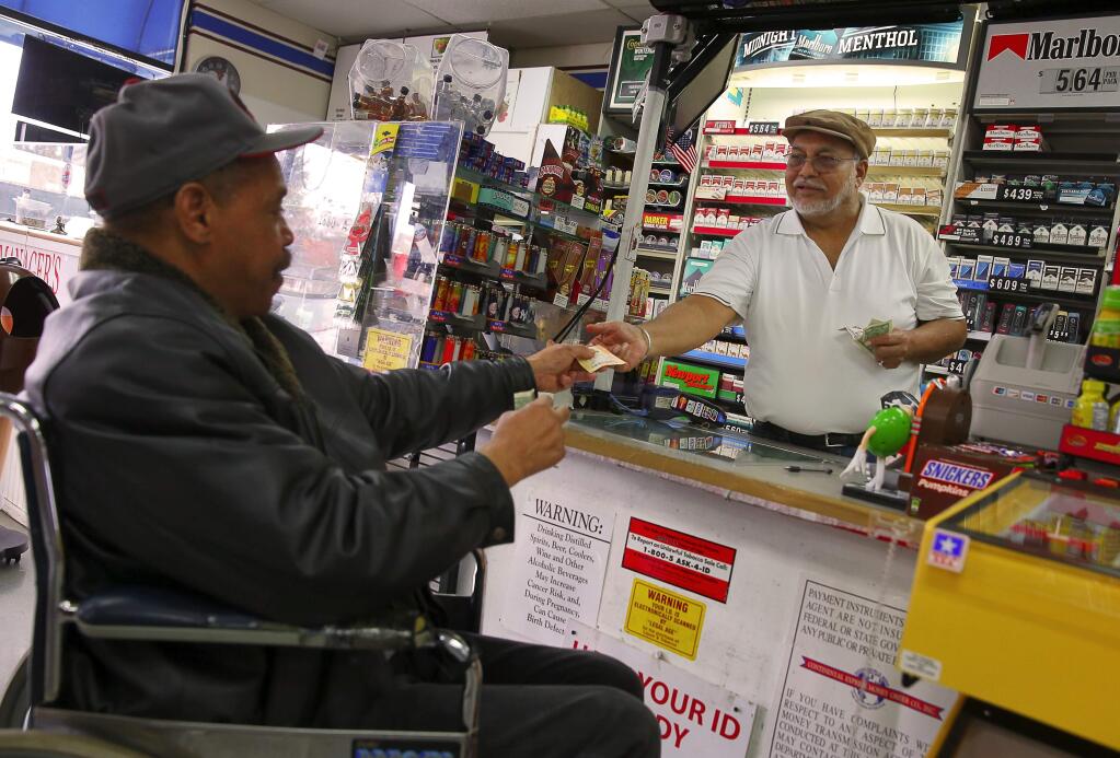 Keith Kelly, left, buys a Powerball lottery ticket from Harbans Singh, owner of Campus Market, in Santa Rosa, on Friday, January 8, 2016. (Christopher Chung/ The Press Democrat)