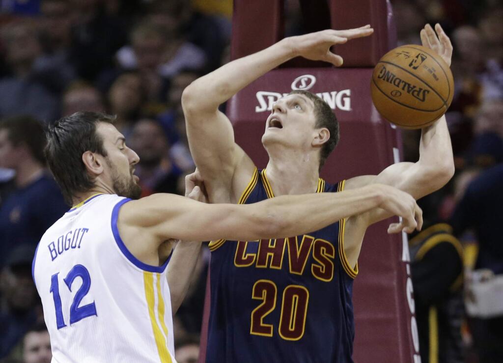 Golden State Warriors' Andrew Bogut (12) knocks the ball loose from Cleveland Cavaliers' Timofey Mozgov (20) during the first quarter of a game Thursday, Feb. 26, 2015, in Cleveland. (AP Photo/Tony Dejak)