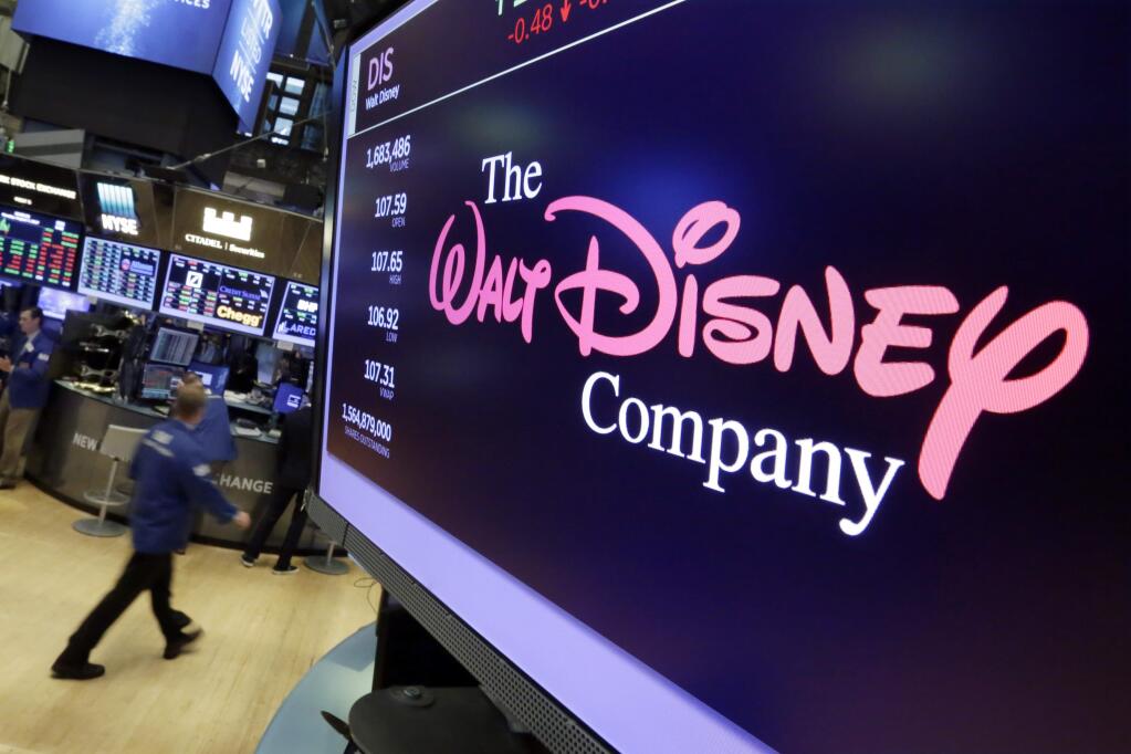 FILE - In this Aug. 8, 2017, file photo, The Walt Disney Co. logo appears on a screen above the floor of the New York Stock Exchange. Disney is making a $70.3 billion counter bid for Fox's entertainment businesses following Comcast's $65 billion offer for the company. (AP Photo/Richard Drew, File)