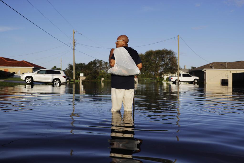 Jean Chatelier walks through a flooded street from Hurricane Irma after retrieving his uniform from his house to return to work today at a supermarket in Fort Myers, Fla., Tuesday, Sept. 12, 2017. Chatelier walked about a mile each way in knee-high water as a Publix supermarket was planning on reopening to the public today. 'I want to go back to work. I want to help,' said Chatelier. (AP Photo/David Goldman)