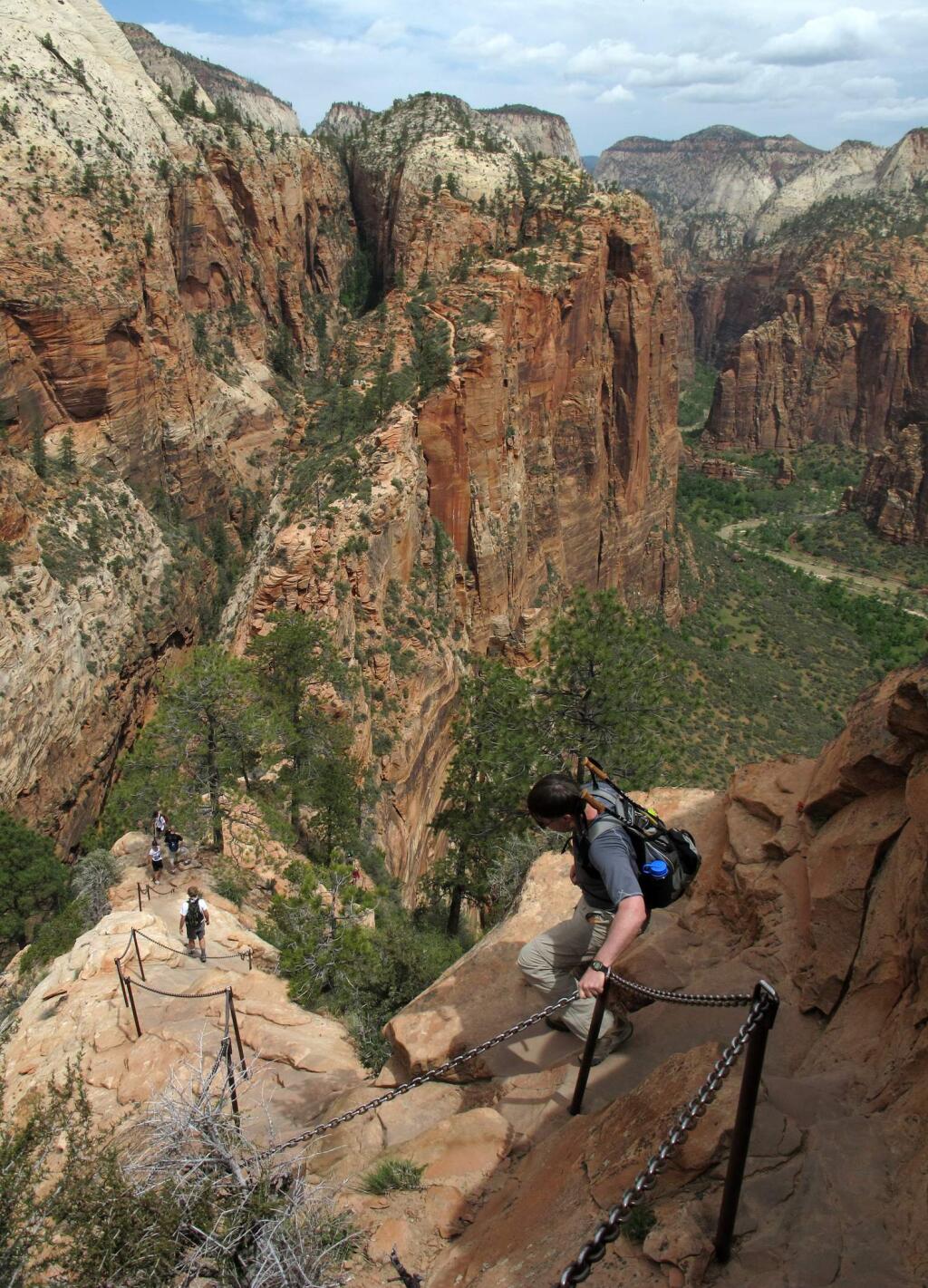 FILE - In this May 8, 2011, file photo, hikers climb down the Angels Landing trail in Zion National Park, in Utah. Zion National Park announced Monday, March 23, 2020, it is closing its campgrounds and part of a popular trail called Angel's Landing that is often crowded with people due to coronavirus. The top part of the hike that is being closed is bordered by steep drops and ascends some 1,500 feet (457 meters) above the southern Utah park's red-rock cliffs, offering sweeping views. (Jud Burkett/The Spectrum via AP, File)