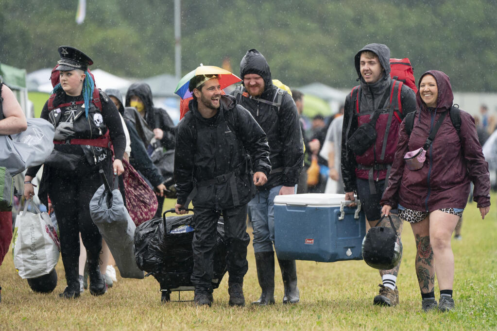 Festivalgoers arrive during a downpour on the first day of Download Festival at Donington Park at Castle Donington, England, Friday June 18, 2021. The three-day music and arts festival is being held as a test event to examine how Covid-19 transmission takes place in crowds, with the the capacity significantly reduced from the normal numbers. (Joe Giddens/PA via AP)