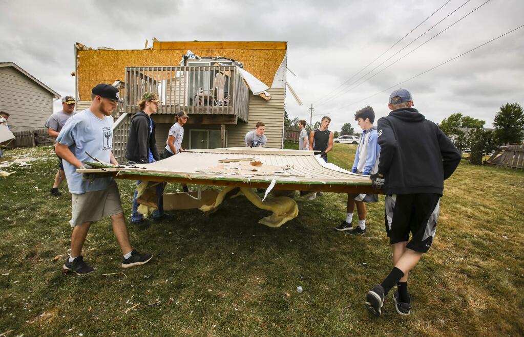 Members of the Bondurant-Farrar football team help cleanup debris on the west end of Bondurant, Iowa, Friday, July 20, 2018, after a tornado slashed through the town the day before. (Rodney White/The Des Moines Register via AP)