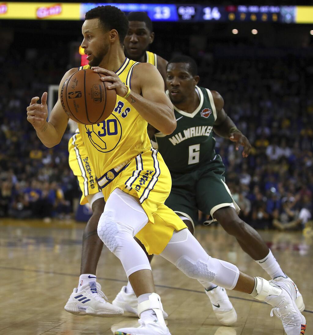 The Golden State Warriors' Stephen Curry drives the ball past the Milwaukee Bucks' Eric Bledsoe during the first half Thursday, Nov. 8, 2018, in Oakland. (AP Photo/Ben Margot)