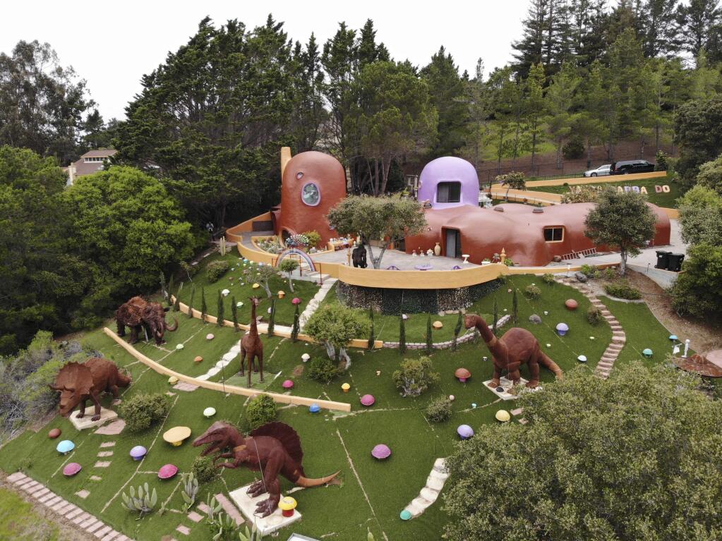 This Monday, April 1, 2019 photo, shows an aerial view of the Flintstone House in Hillsborough, Calif. The San Francisco Bay Area suburb of Hillsborough is suing the owner of the house, saying that she installed dangerous steps, dinosaurs and other Flintstone-era figurines without necessary permits. The owner and her attorney say they will fight for the rights of property owners and Fred and Barney fans everywhere. (AP Photo/Terry Chea)