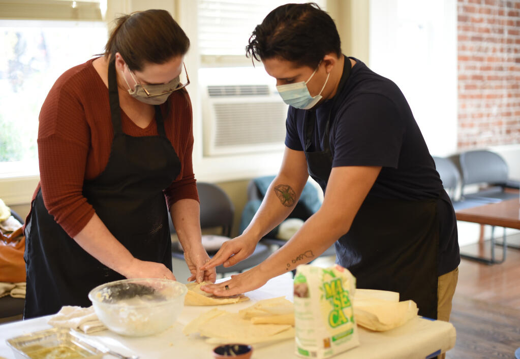 Culinary student Chrissy Brady, left, getting some assistance from Erik Mejia, owner of Ta'Bueno Co., during his tamale class taught at the Sonoma Community Center in Sonoma, Calif., on Saturday, Dec. 11, 2021. ( Erik Castro/for The Press Democrat)