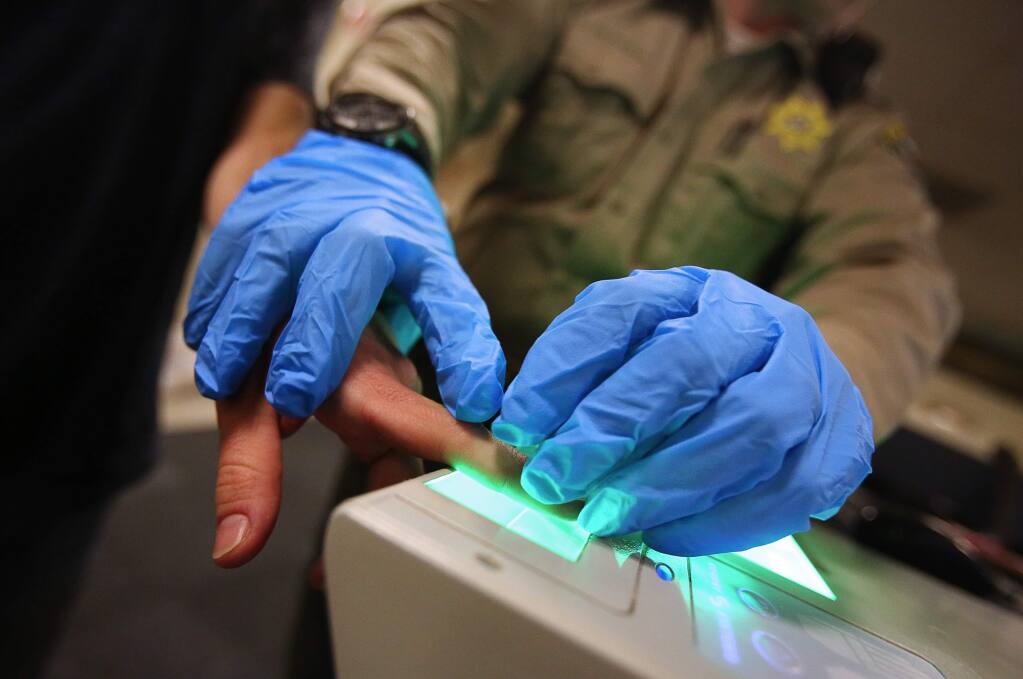 An individual is fingerprinted by a Sonoma County Sheriff's deputy while being processed at the Main Adult Detention Facility, in Santa Rosa, on Thursday, February 9, 2017. (Christopher Chung/ The Press Democrat)