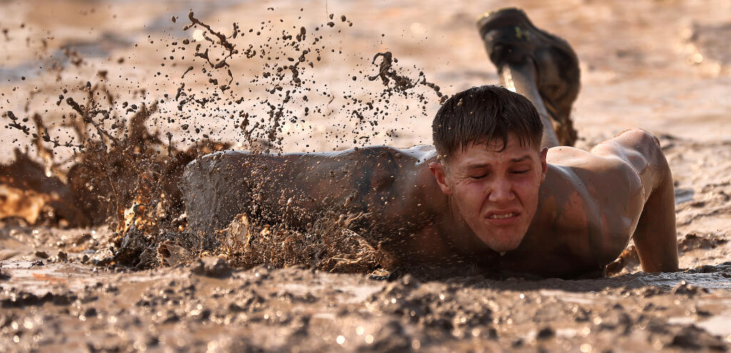 Thick mud envelops participants in the barbwire encased Kiss of Mud during the Tough Mudder, Saturday, Aug. 28, 2021 at Sonoma Raceway.  (Kent Porter / The Press Democrat) 2021