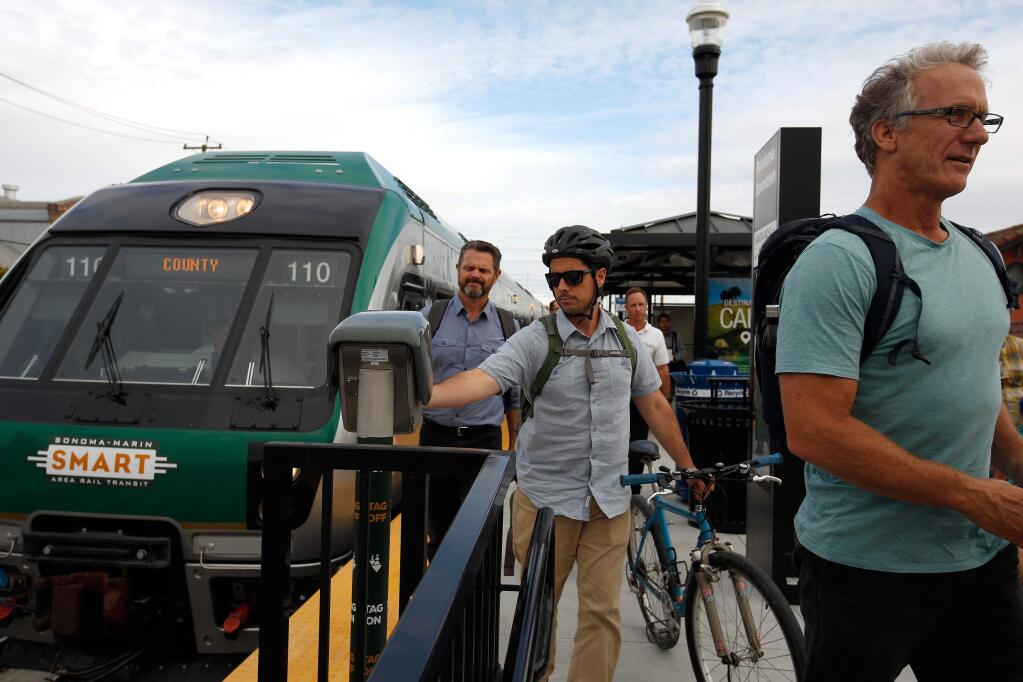 Craig Richardson, center, of Petaluma and other SMART train commuters use their Clipper cards to tap off the train as they exit the station in Petaluma, California, on Wednesday, September 20, 2017. (Alvin Jornada / The Press Democrat)
