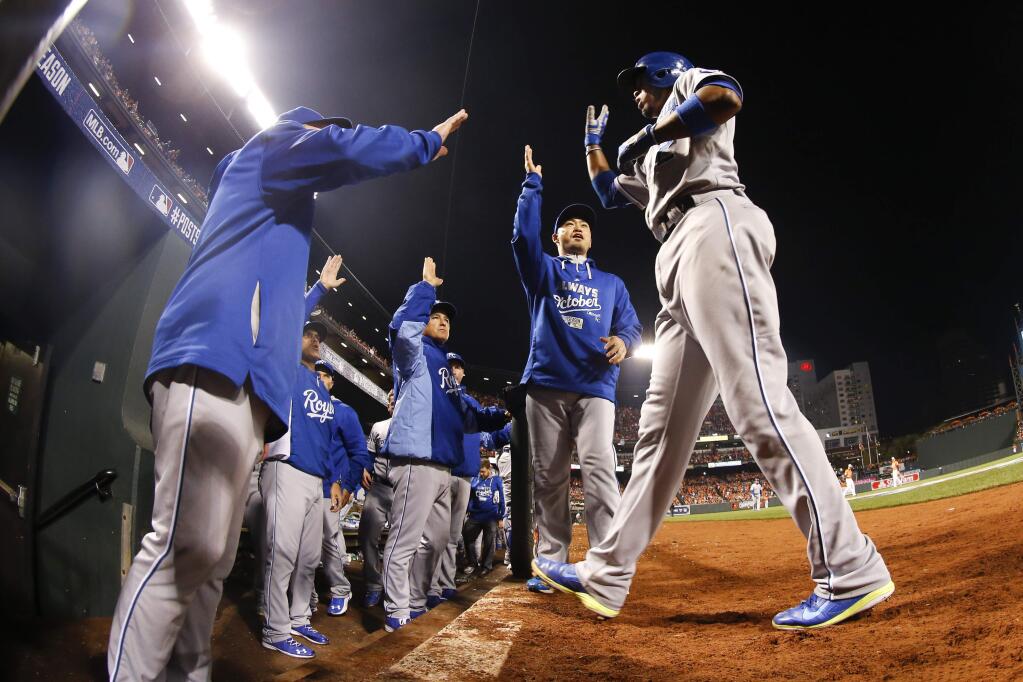 Kansas City Royals' Alcides Escobar is congratulated by teammates after scoring during the ninth inning of Game 2 of the American League baseball championship series against the Baltimore Orioles Saturday, Oct. 11, 2014, in Baltimore. (AP Photo/Matt Slocum)