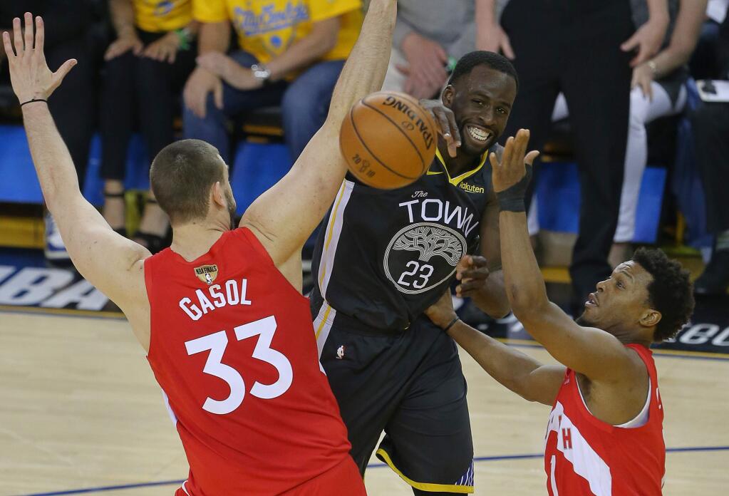 Golden State Warriors forward Draymond Green passes the ball between Toronto Raptors center Marc Gasol and guard Kyle Lowryduring game 4 of the NBA Finals in Oakland on Friday, June 7, 2019. (Christopher Chung/ The Press Democrat)