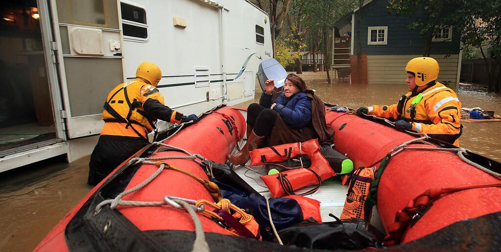Russian River Fire Protection District firefighters Ryan Lantz and Mark Haas rescue 84 year-old Eve Cerqua from her flooded trailer at the Sycamore Court Apartments in Guerneville after a rapid rise in flood waters, Tuesday Afternoon January 10, 2017. (Kent Porter / The Press Democrat) 2017