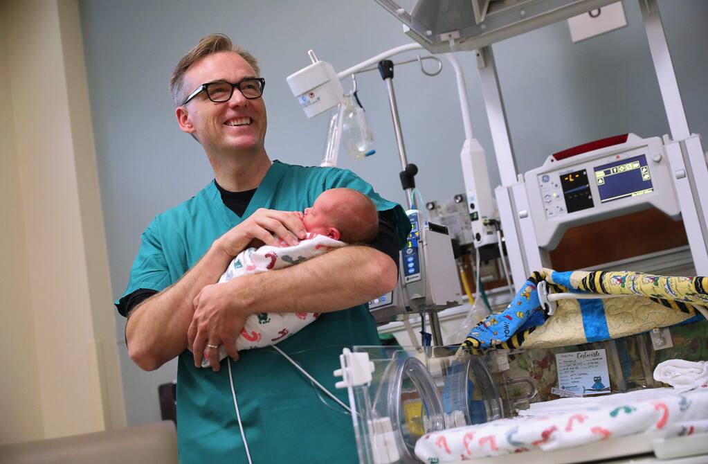 Neonatal physician Dr. Scott Witt, holding newborn Bryson Entwisle, helped to evacuate the Sutter Santa Rosa Regional Hospital's Neonatal Intensive Care Unit as the Tubbs Fire closed in. Witt and his family lost their Fountaingrove home to the fire after evacuating. Entwisle was not one of the babies evacuated. (Christopher Chung/ The Press Democrat)