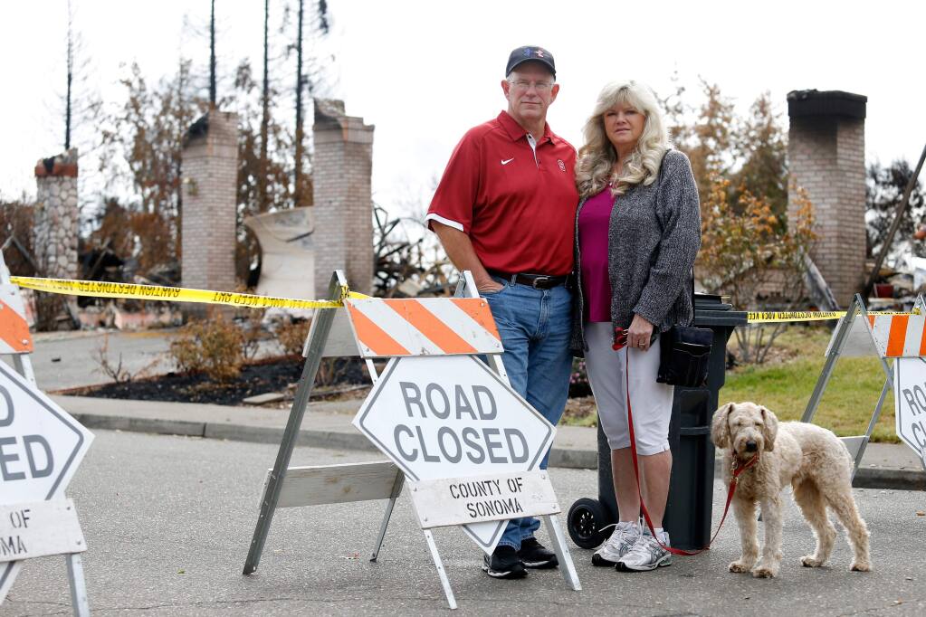 Mark West Estates residents Brett and Cheryl Gripe, with their dog Major, pose for a portrait at a roadblock on Lambert Drive, which leads into their Larkfield-Wikiup neighborhood, in Santa Rosa, California on Friday, October 20, 2017. (Alvin Jornada / The Press Democrat)