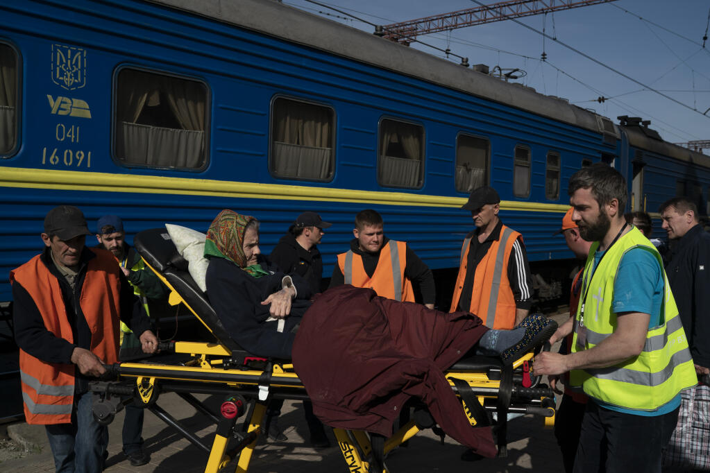 An elderly woman is carried on a stretcher before boarding a train at a train station in Pokrovsk, Ukraine, Monday, April 25, 2022, to flee the war in Severodonetsk and nearby towns. Russia unleashed a string of attacks against Ukrainian rail and fuel installations Monday, striking crucial infrastructure far from the front line of its eastern offensive. (AP Photo/Leo Correa)