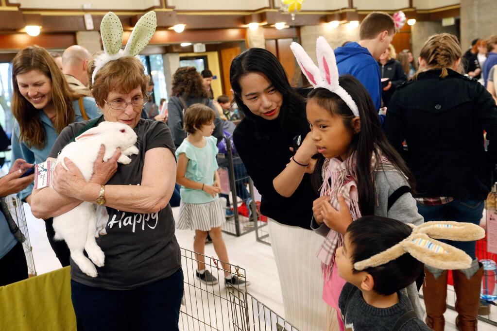 Sonoma Humane Society volunteer Mariana Moats, left, holds a bunny while talking with Tracy Ding of Santa Rosa and her children Rachel, 11, and Jasper, 4, during Bunfest at Burton Avenue Recreation Center in Rohnert Park, California, on Saturday, April 8, 2017. (Alvin Jornada / The Press Democrat)