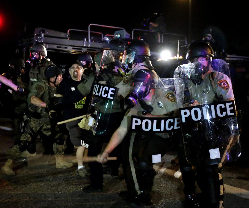 A man is detained after a standoff between protesters and police Monday, Aug. 18, 2014, during a protest for Michael Brown, who was killed by a police officer Aug. 9 in Ferguson, Mo. Brown's shooting has sparked more than a week of protests, riots and looting in the St. Louis suburb. (AP Photo/Charlie Riedel)