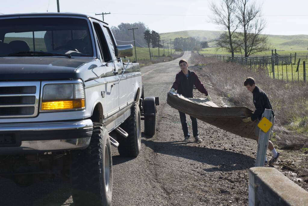 Cardinal Newman High School students Harrison Greenleaf, 15, left, and Porter Tett, 14, help load a moldy rain-soaked mattress found on Spring Hill Road in Petaluma into Keith Marchando's truck Sunday morning, Feb. 21, 2016. The three are part of a group of volunteers for Tour de Trash, which collects illegally dumped items. (Erik Castro/for The Press Democrat)