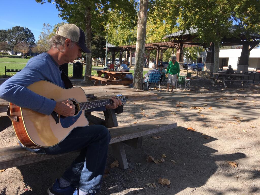 Michael Holmes, 72, passes time quietly on Tuesday, playing his guitar on the Windsor Town Green. Though trouble could follow the election, he said, “I would hope the overwhelming majority would not go along with it.” (Chris Smith / The Press Democrat)