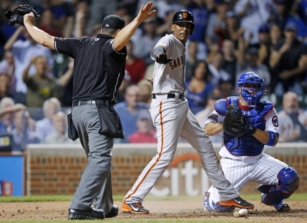 San Francisco Giants' Joaquin Arias, center, is called safe by home plate umpire Mike DiMuro, left, after scoring past Chicago Cubs catcher Welington Castillo, right, on a hit by Madison Bumgarner during the fourth inning of a baseball game on Thursday, Aug. 21, 2014, in Chicago. (AP Photo/Andrew A. Nelles)