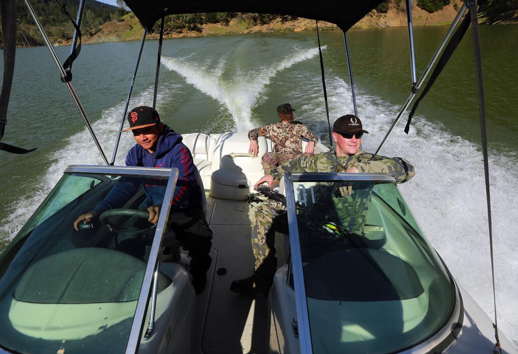 Guide Jayson Collard, back and Tyler Nackord take a boat shuttle back to the Lake Sonoma marina after a successful archery pig hunt. (JOHN BURGESS/The Press Democrat)