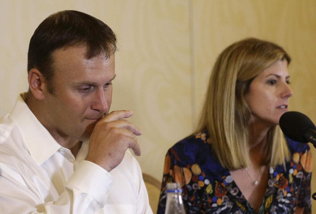 Former Miami Dolphins fullback Rob Konrad, left, listens while his wife Tammy, right, responds to a question during a news conference where he told about his ordeal of swimming nine miles to shore after he fell off his boat while fishing last week off the South Florida coast, Monday, Jan. 12, 2015, in Plantation, Fla. Konrad fell off his 36-foot-boat while fishing alone. The boat was on auto pilot and floated away. (AP Photo/Lynne Sladky)