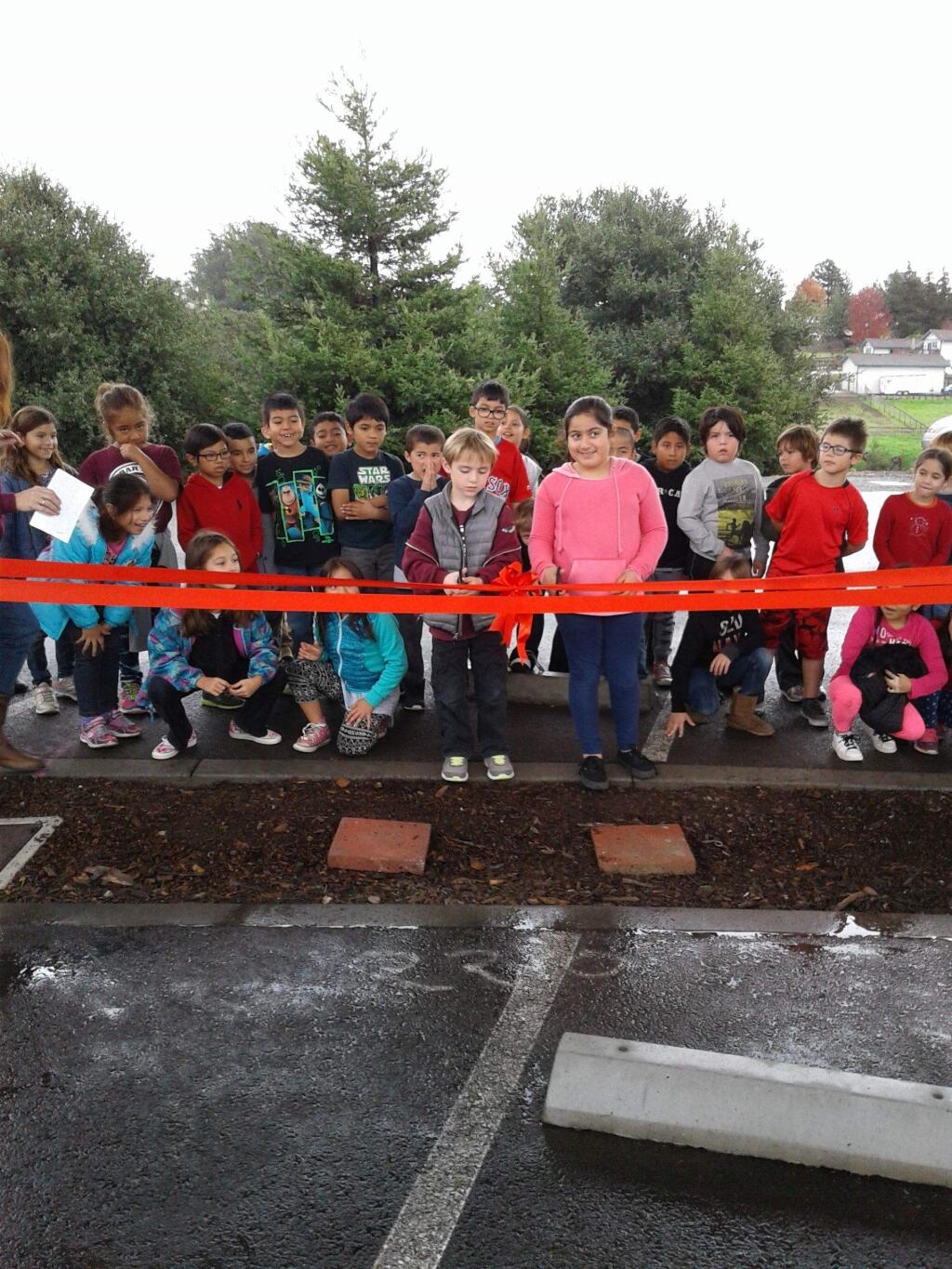 JOHN JACKSON/ARGUS-COURIER STAFFSkye Downing andPaola Resendiz-Valdez lead Cinnabar School second graders in cutting the ribbon for new solar panels that will save their school an estimated $20,000 a year in energy costs.